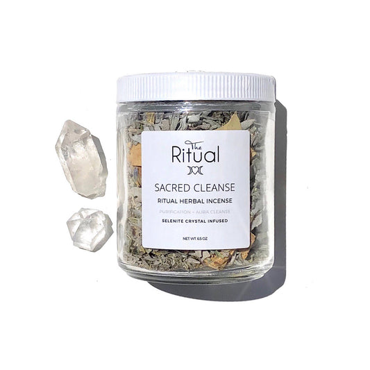 A clear jar containing herbal incense with a white label that reads 'SACRED CLEANSE RITUAL HERBAL INCENSE'. There are pieces of white and blue sage, cedar, eucalyptus, and palo santo visible within the jar.